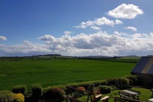 a view of a large green field with a house at Rocking Chair Farmhouse in Alnwick