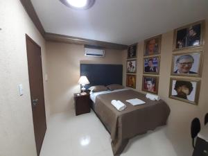 een slaapkamer met een bed en foto's aan de muur bij Hotel Nacional in Sobral