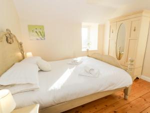 a bedroom with a bed with white sheets and a dresser at Lapwing Cottage in Dalbeattie