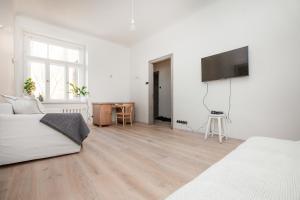 Habitación blanca con cama y TV de pantalla plana. en Ascetic Skolas Street Apartment en Riga