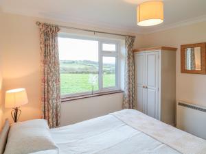 a bedroom with a bed and a large window at Little Lanes in Camelford