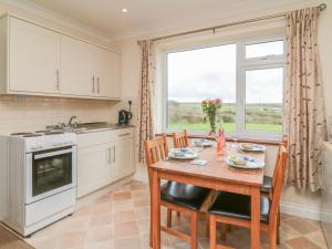 een keuken met een tafel en stoelen en een raam bij Little Lanes in Camelford