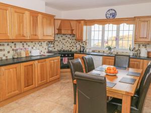 una cocina con armarios de madera y una mesa con un bol de fruta en Erris Head House, en Belmullet
