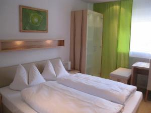 a white bed in a room with a green wall at Hotel Barbarina in Tübingen