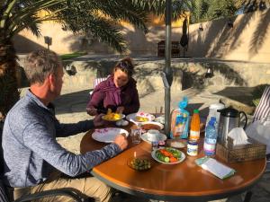 a man and a woman sitting at a table with food at The Wadi Inn in Al Ḩamrāʼ