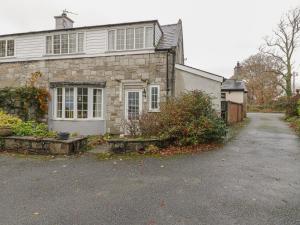 a stone house with a driveway in front of it at Corner Cottage in Beaumaris
