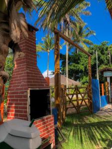 a brick oven in a yard with a fence and palm trees at Pousada Pôr do Sol in Barra Grande