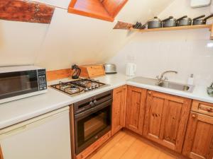 uma cozinha com um fogão e um lavatório em The Granary em Llandyfrydog