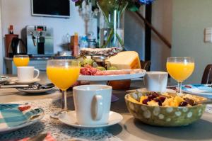 a table with a plate of food and glasses of orange juice at PuurTeuven B&B tussen Kunst en Natuur in Voeren