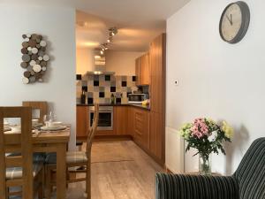 una cucina con tavolo e orologio sul muro di 37 Farraline Court, City Centre apartment a Inverness