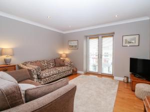 a living room with a couch and a tv at 10 Pen Llanw Tides Reach in Rhosneigr