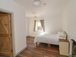 a white bedroom with a bed and a window at Macreddin Rock Holiday Cottage in Aughrim