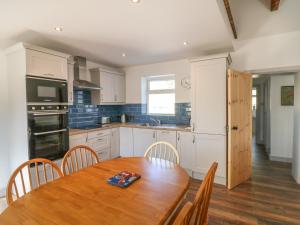 a kitchen with a wooden table with chairs and a wooden floor at Macreddin Rock Holiday Cottage in Aughrim