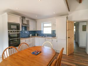 una cucina con tavolo in legno, sedie e pavimento in legno di Macreddin Rock Holiday Cottage a Aughrim