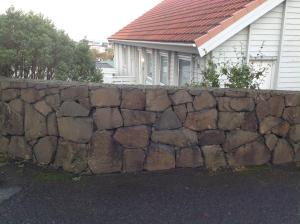 a stone retaining wall in front of a house at Marna Luxus Guesthouse doubleroom nr.3 in Tórshavn