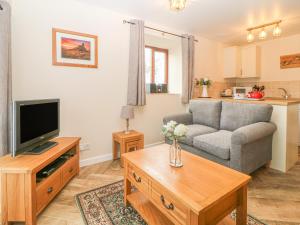 a living room with a couch and a tv at Hilly Field Barn in Yelverton