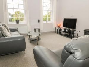 a living room with a couch and a television at The Sea Chest in Alnwick