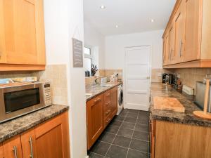 a kitchen with wooden cabinets and a microwave at Cranberry in Bude