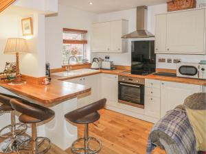 a kitchen with white cabinets and a counter with bar stools at Chuckle Cottage in Northallerton