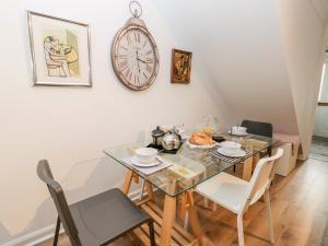 a dining room with a table and chairs and a clock at Rosewood Cottage in Bridlington