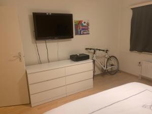 um quarto com uma cómoda, uma televisão e uma bicicleta em nice and cosy apartment em Edegem