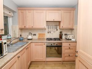 a kitchen with wooden cabinets and a stove top oven at Allam Cottage in Barnard Castle