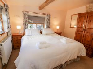 a bedroom with a large white bed with two towels on it at The Byre in Llandyfrydog