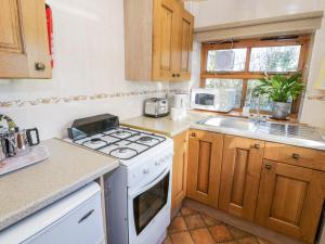 a kitchen with a stove and a sink at The Byre in Llandyfrydog