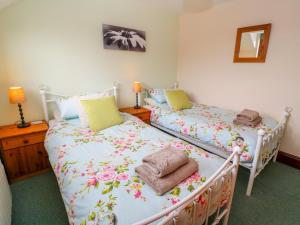 a bedroom with two beds with flowers on them at Mossley Cottage in Penzance