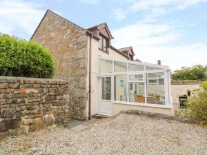 a stone house with a large window and a stone wall at Mossley Cottage in Penzance