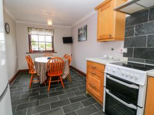 a kitchen with a table and chairs and a stove at Mossley Cottage in Penzance