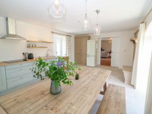 a kitchen with a wooden table with a vase of flowers at Old Village Barn in Woodford