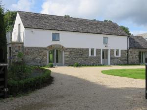 an old stone house with a gravel driveway at Old Village Barn in Woodford