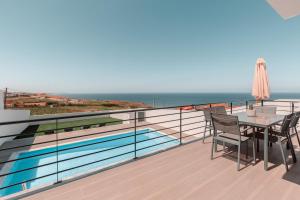 a balcony with a table and chairs and the ocean at Silver Villa in Lourinhã