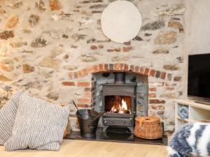 a fireplace in a living room with a stone wall at Ty ar Ben Bryn in Llanfaelog