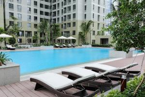 une piscine avec des chaises longues et un hôtel dans l'établissement High Class 2 Bedrooms Masteri Thao Dien Apartment, Fully Furnished With Full Amenities, à Hô-Chi-Minh-Ville