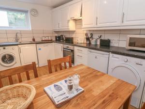 uma cozinha com armários brancos e uma mesa de madeira em Riverside Cottage em Falmouth