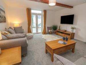een woonkamer met een bank en een tv bij Riverside Cottage in Falmouth