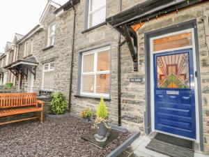 a blue door on a brick house with a bench at Yr Adfa The Retreat in Blaenau-Ffestiniog