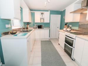 a white kitchen with blue walls and white cabinets at Yr Adfa The Retreat in Blaenau-Ffestiniog +9 photos