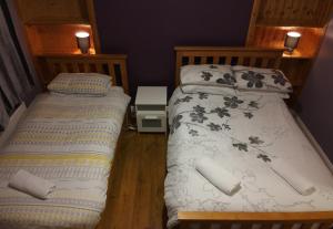 two twin beds in a room with two lamps at Helens Self Catering in Castlebar