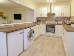 a kitchen with white cabinets and a washer and dryer at Beside The Sea - In Town in Llandudno