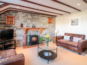 a living room with a fireplace and leather furniture at Polkirt Forge in Mevagissey