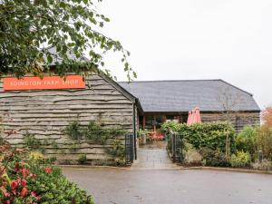 ein Gebäude mit einem Schild, das auf einem purpurnen Hofladen steht in der Unterkunft Tilly's Cottage in Westbury