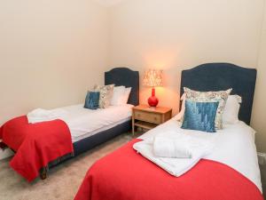 two beds in a room with a red blanket at South Tower Cottage in Macclesfield