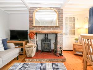 a living room with a brick fireplace and a tv at Fisherman's Cottage in Pevensey