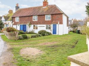 una casa con puertas azules y un patio en Fisherman's Cottage en Pevensey