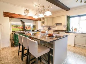 a kitchen with white cabinets and a large island with chairs at Squires Rest in Welshpool