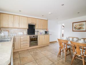 a kitchen with wooden cabinets and a table and chairs at The Old Cook House in Penrith