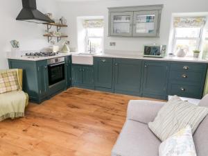 cocina con armarios verdes y suelo de madera en 4 Castle View, en Barnoldswick